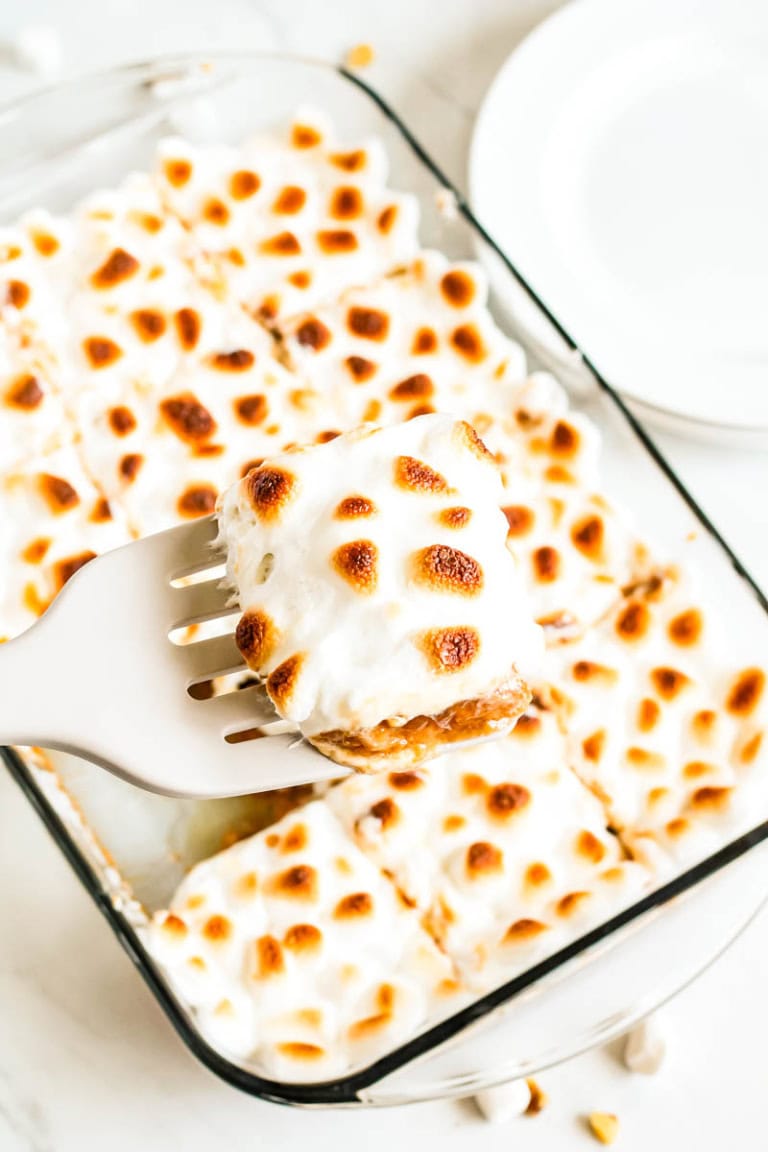Sweet potato casserole slice being lifted out of pan with a spatula.