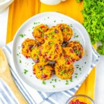Stuffing balls stacked on a white plate on a cutting board with cilantro in the background.