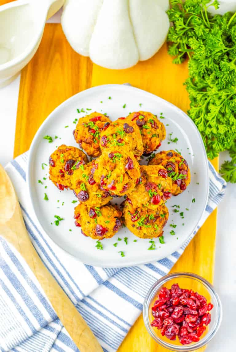 Stuffing balls stacked on a white plate on a cutting board with cilantro in the background.