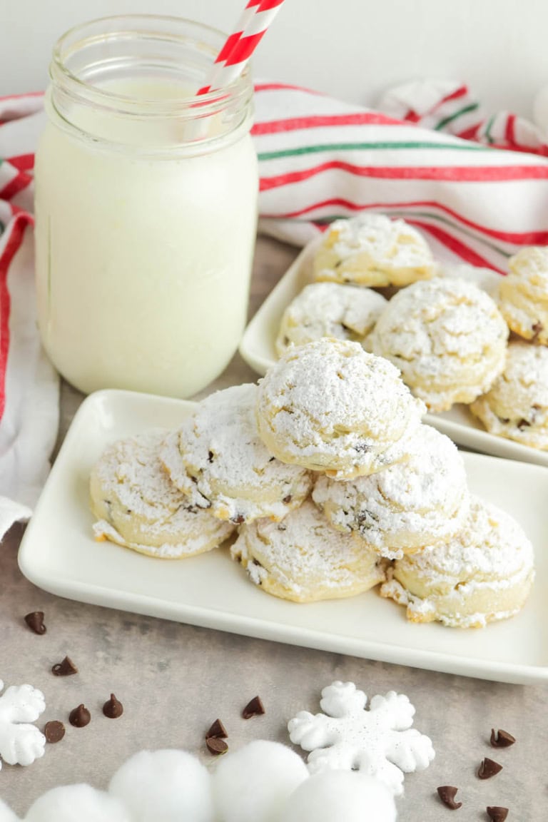 Gluten free snowball cookies on a white plate with glass of milk beside and a red, white and green strip towel