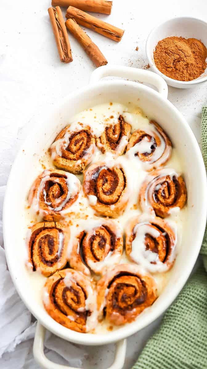 White baking dish with cinnamon rolls that are iced.