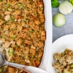 Casserole dish with gluten free thanksgiving stuffing and a metal spoon with plate next to dish with stuffing on it