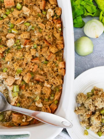 Casserole dish with gluten free thanksgiving stuffing and a metal spoon with plate next to dish with stuffing on it
