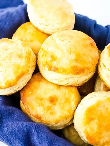 Gluten free buttermilk biscuits in a pan sitting on a blue towel.