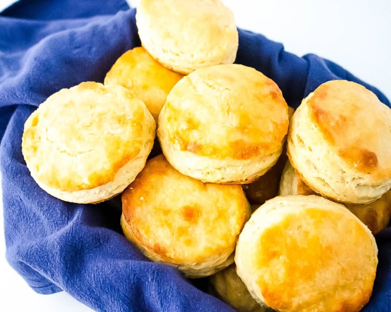 Gluten free buttermilk biscuits in a pan sitting on a blue towel.