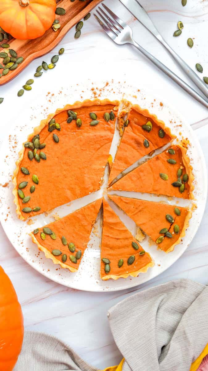 Gluten free pumpkin pie on white plate with five slices cut.