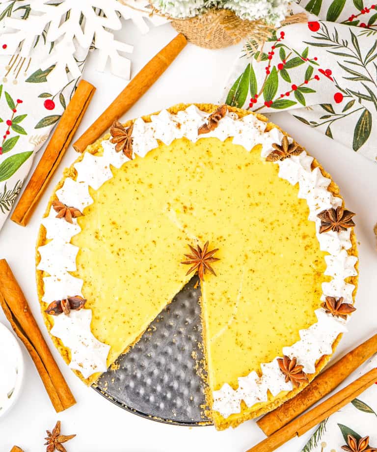No bake eggnog pie with slice cut out of pie and cinnamon sticks surrounding the pie