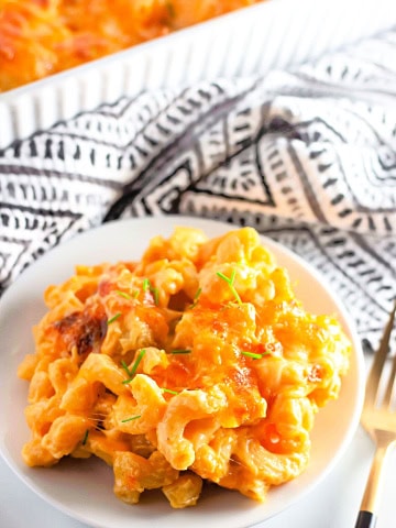 A plate of gluten free macaroni and cheese on white with black and white towel in background.