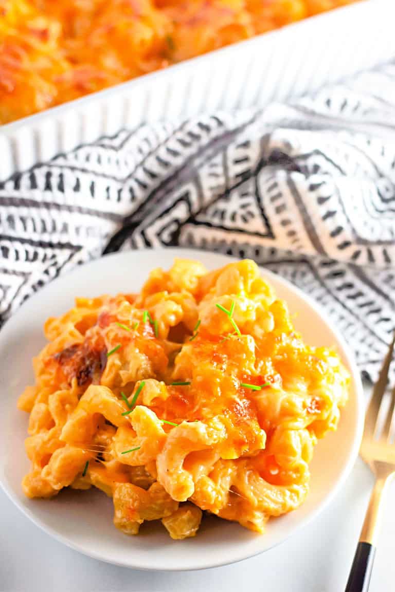 A plate of gluten free macaroni and cheese on white with black and white towel in background.