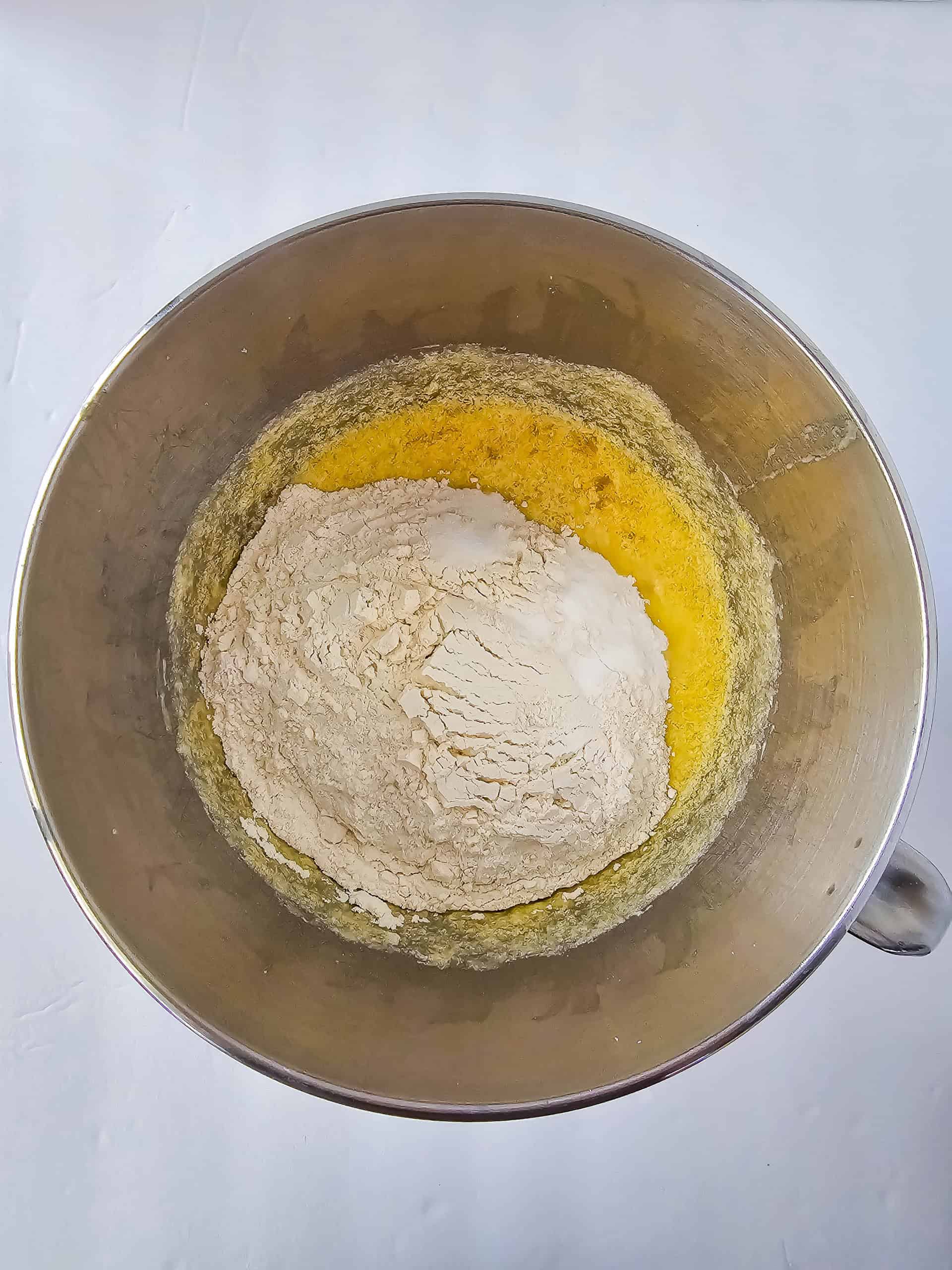 A bowl with the flour and baking soda on top of the banana/egg mixture.
