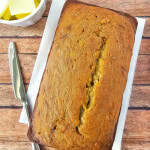 Loaf of gluten free banana bread on wooden background with knife and butter aside.