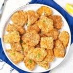 White plate on a blue napkin full of chicken nuggets