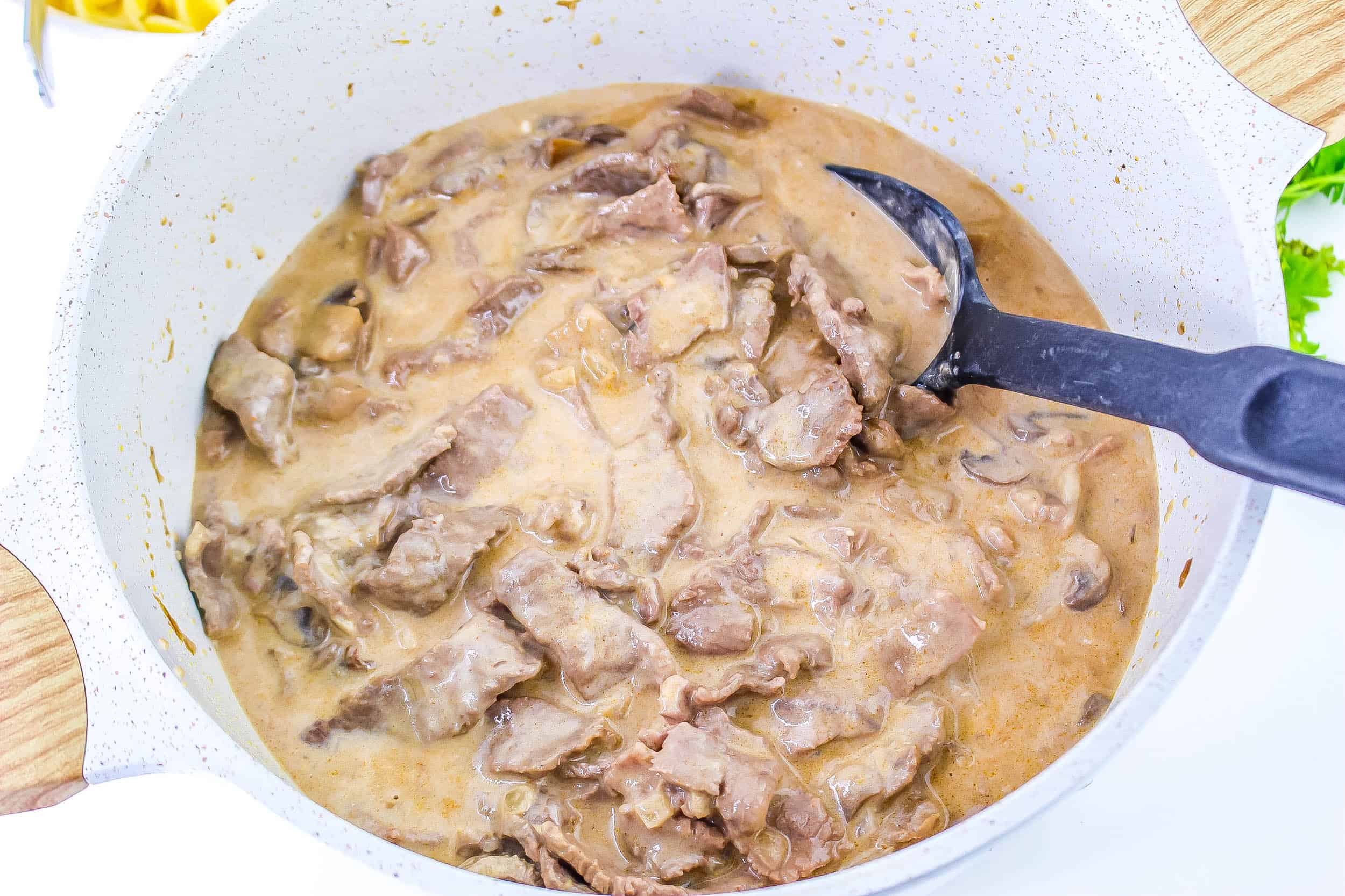 Sour cream stirred into the beef stroganoff sauce in the dutch oven