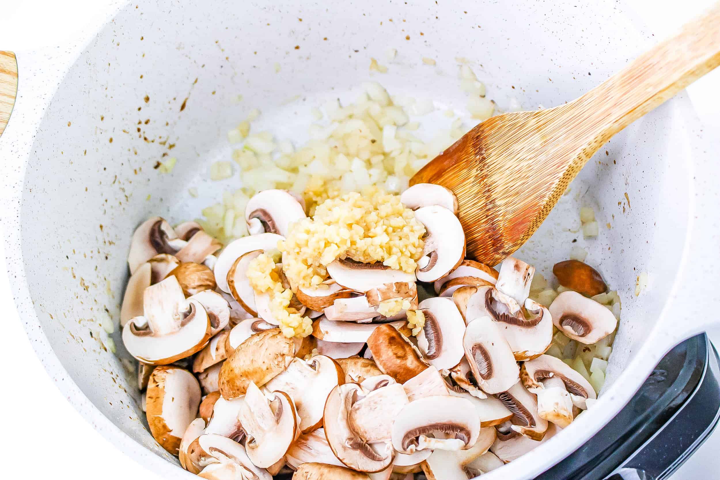 Onions, mushrooms and garlic in the dutch oven sauteing.