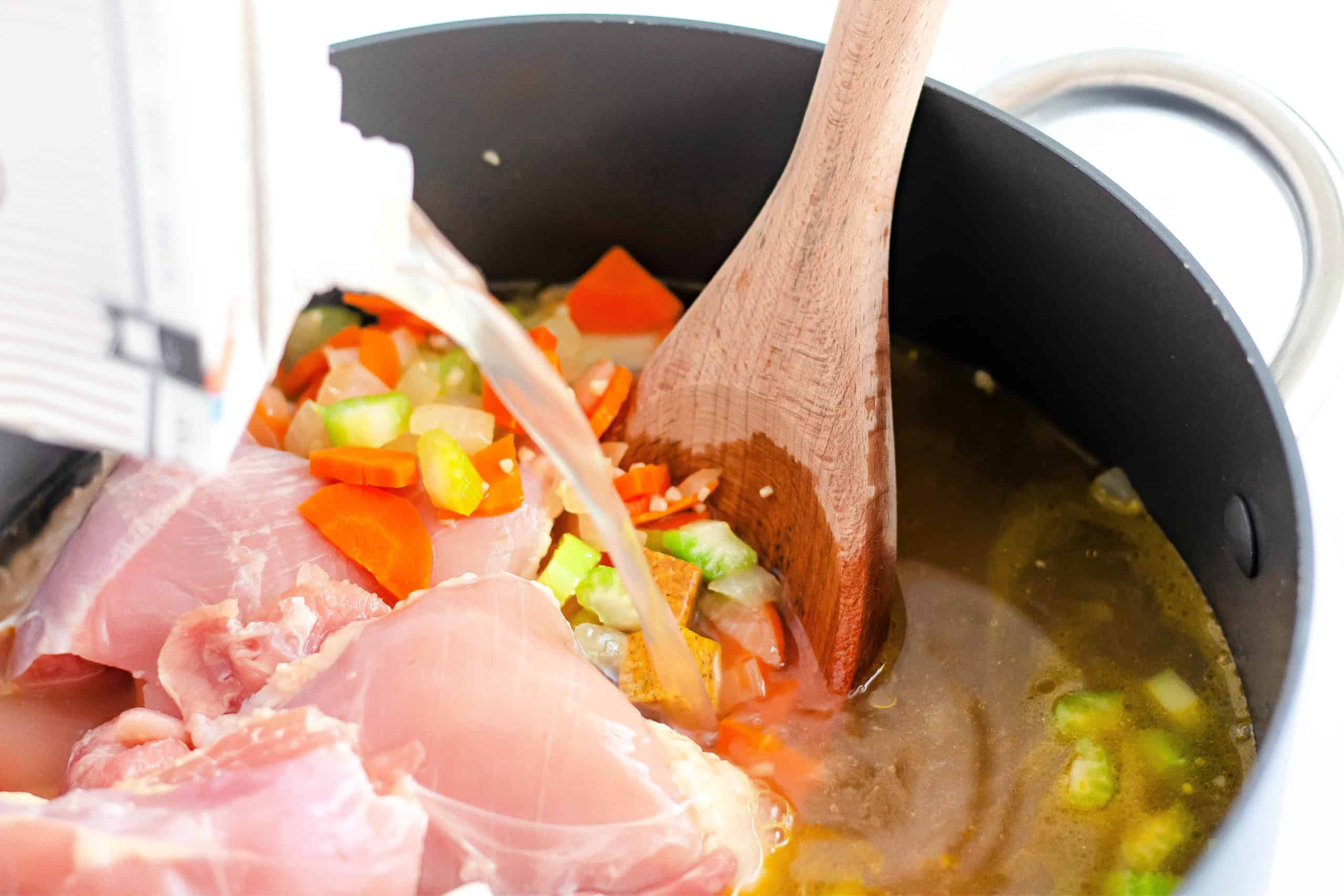 The broth and chicken thighs going into the vegetable mixture.