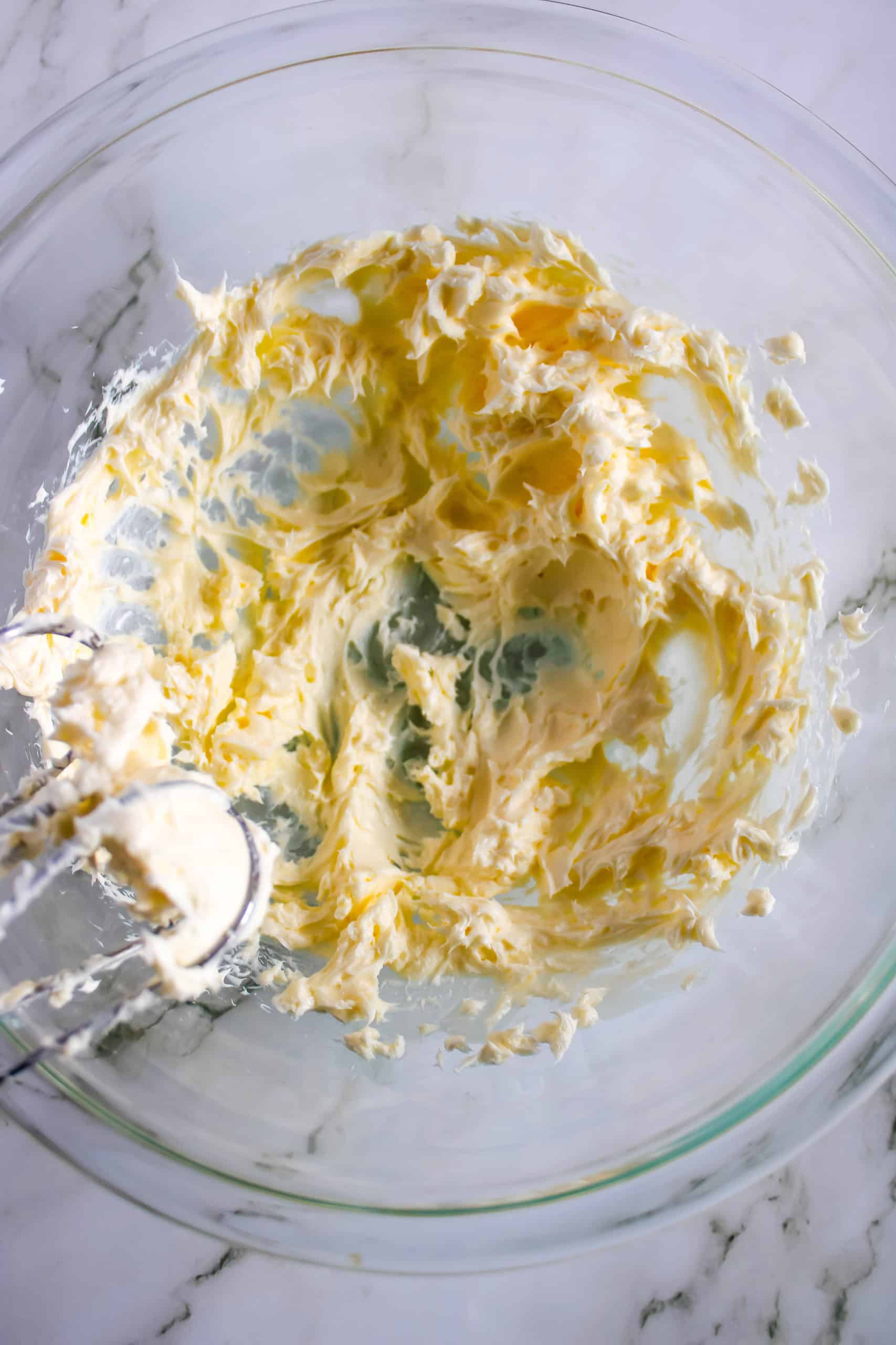 Cream cheese and butter whisked together in glass bowl.
