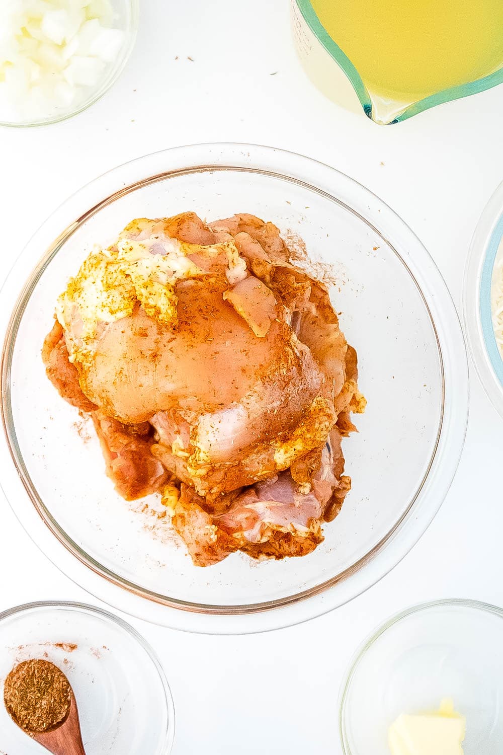 A glass bowl with the chicken and seasonings.