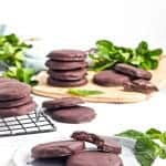 Gluten free thin mint cookies on white board with mint placed around them.