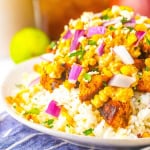 A bowl piled high with the Mexican street corn, chicken and rice.