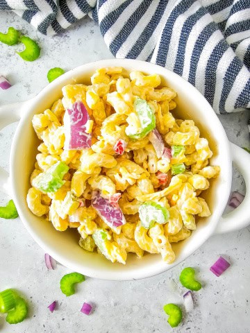 Bowl of gluten free macaroni salad with blue and white strip towel