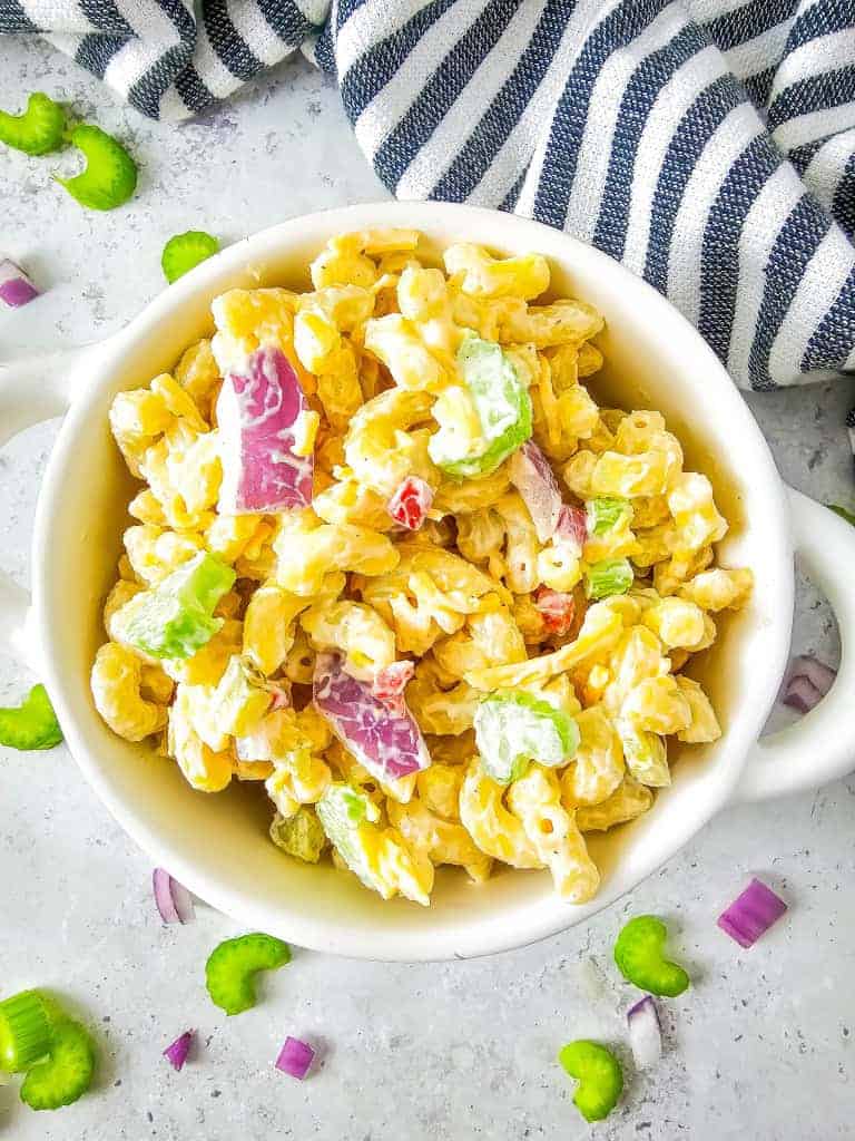Bowl of gluten free macaroni salad with blue and white strip towel