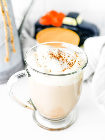 A mug with pumpkin spice chai latte with whipped cream and cinnamon on top